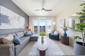 A modern living room with a grey sofa, a coffee table, and a large abstract painting. - Modern 2BR w/ Pool + Pet-Friendly | Unit #19 (Tampa)