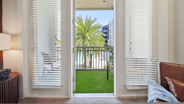 A room with a view of a balcony, a chair, and a lamp. - Modern 2BR w/ Pool | Pet-Friendly | Unit #17 (Tampa)