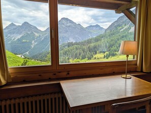 A room with a wooden table, a radiator, and a window with a view of mountains and forest. - Chalet zum Stöckli by Arosa Holiday Appartement/Fewo, Dusche oder Bad, WC, 6-Bet by Interhome (Arosa)