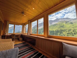 Ein gemütliches Zimmer mit Holzwänden und großen Fenstern mit Blick auf die Berge.
