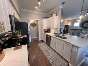 A modern kitchen with a marble countertop, stainless steel appliances, and a patterned rug. - Cozy 1-bedroom condo, close to Sabino Canyon and great restaurants (Tucson)
