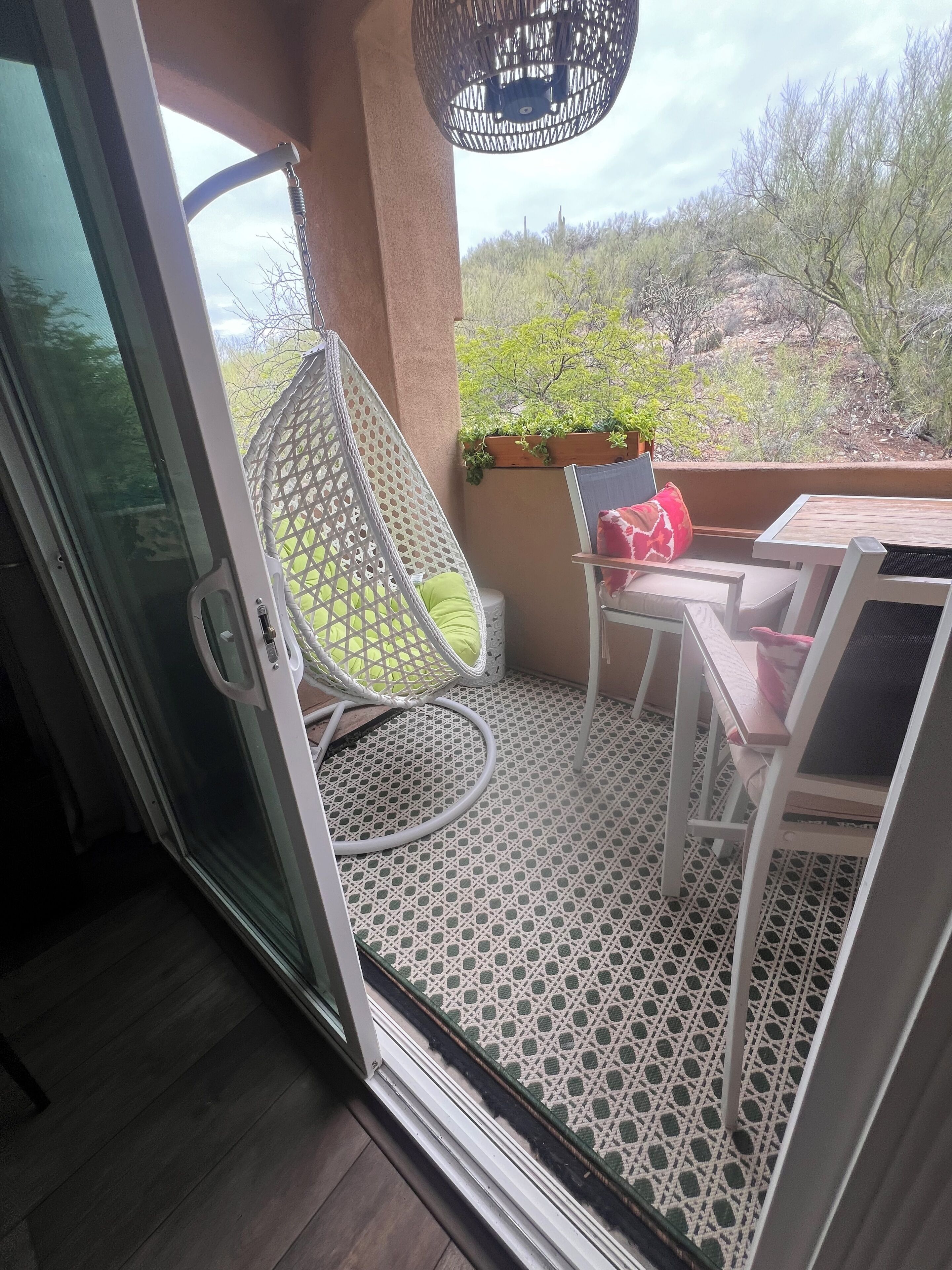 Een balkon met een witte stoel, een tafeltje en een plant in pot.