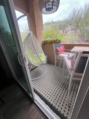 Ein Balkon mit einem weißen Stuhl, einem kleinen Tisch und einem Blumentopf.