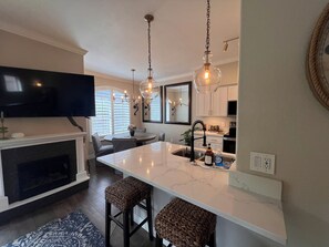 A modern kitchen with a large island, pendant lights, a flat-screen TV, and a fireplace. - Cozy 1-bedroom condo, close to Sabino Canyon and great restaurants (Tucson)