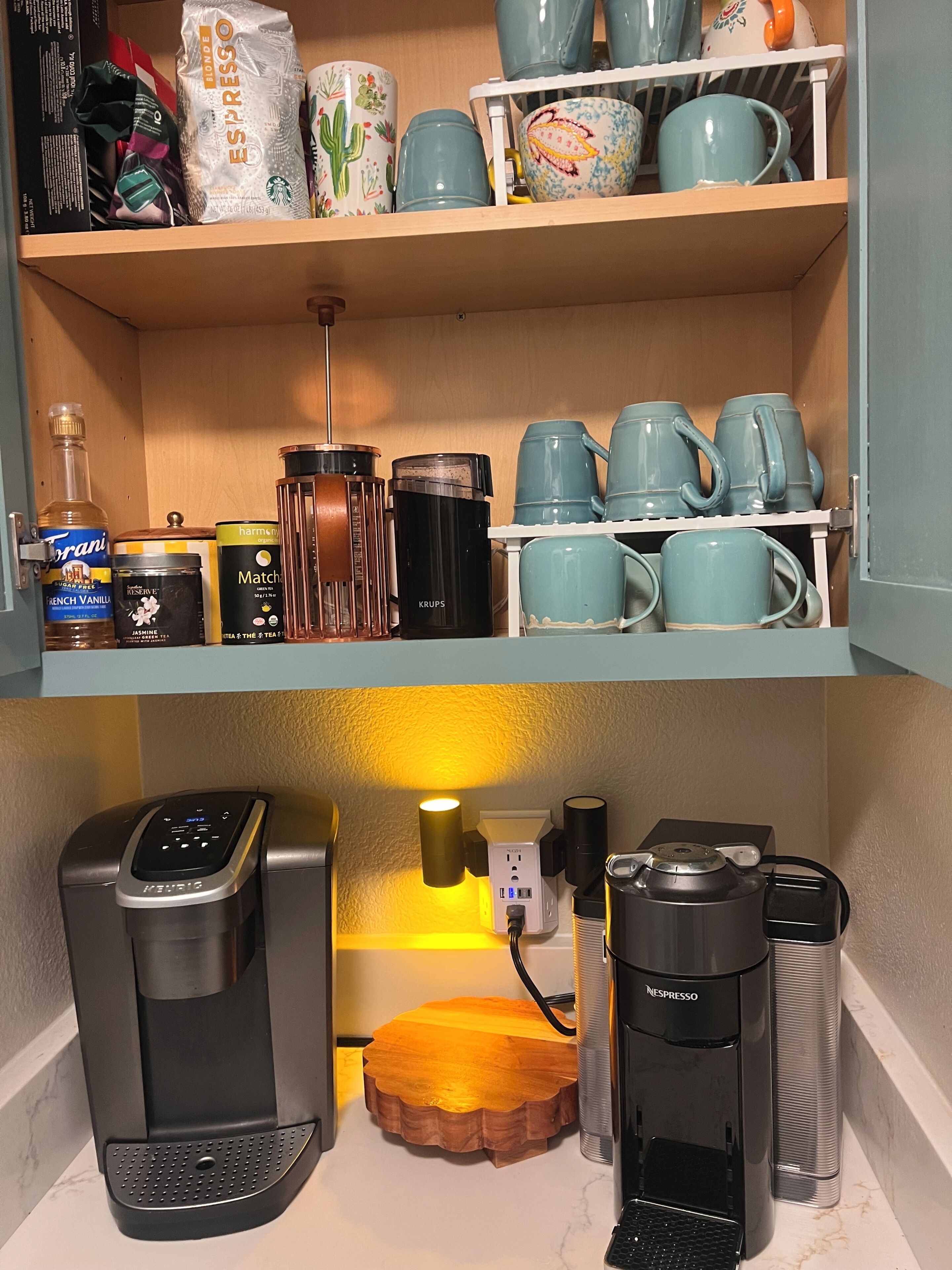 Een keukenhoek met een koffieapparaat, een waterkoker en een koffiemachine op het aanrecht.