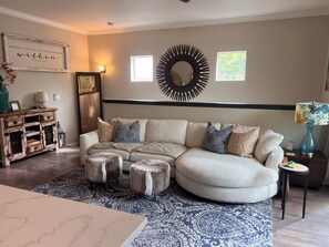 A living room with a sectional sofa, a patterned rug, a decorative mirror, and a side table with a lamp. - Cozy 1-bedroom condo, close to Sabino Canyon and great restaurants (Tucson)