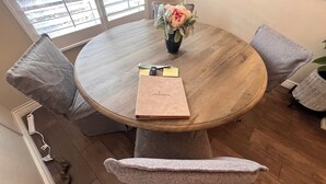 Ein runder Holztisch mit Blumen in einer Vase, einem Notizbuch und einem Stift.