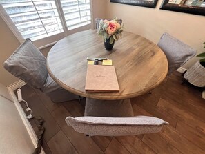 A round wooden table with a vase of flowers, a notebook, and a pen. - Cozy 1-bedroom condo, close to Sabino Canyon and great restaurants (Tucson)