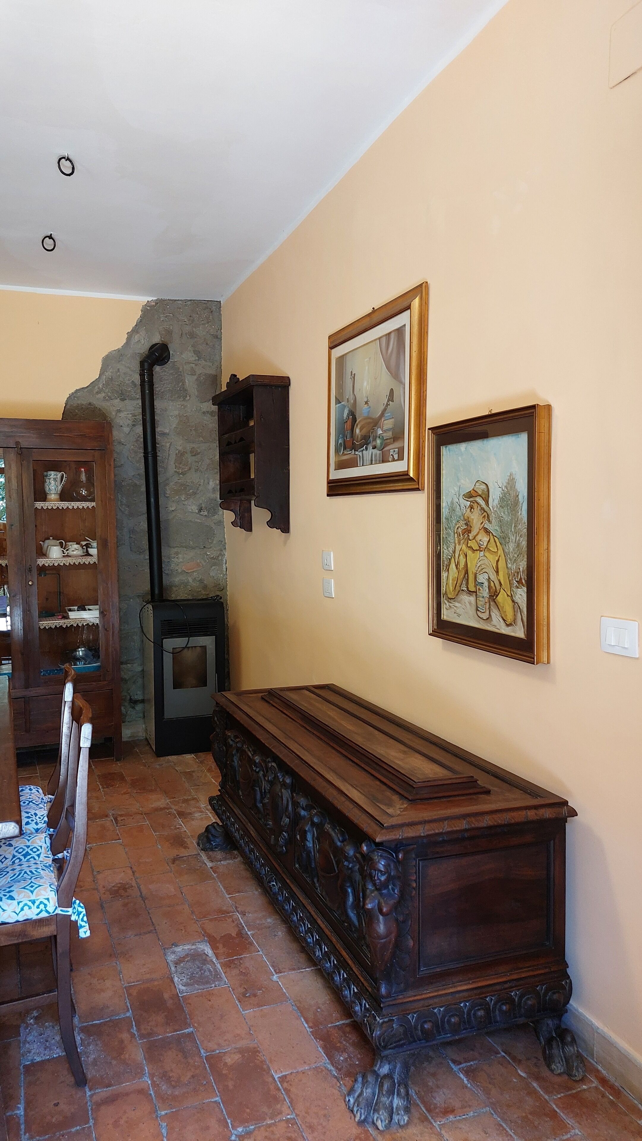 Une pièce avec un banc en bois, un mur en pierre et deux tableaux encadrés accrochés au mur.