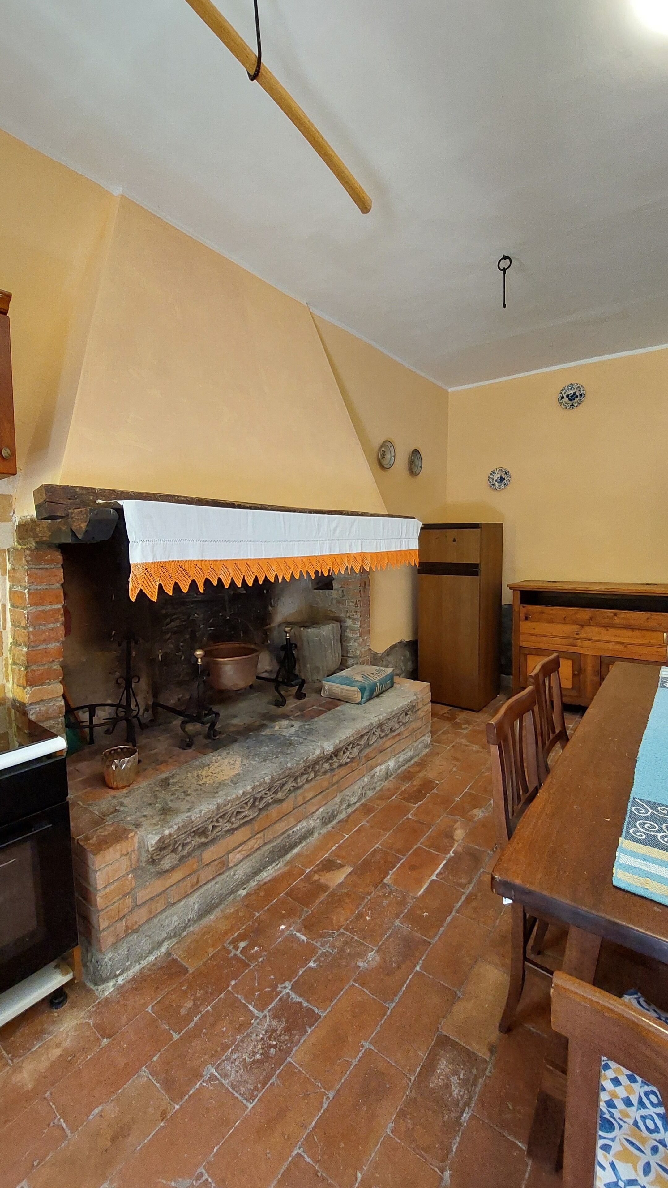 Una cucina rustica con un forno a mattoni, mobili in legno e un pavimento piastrellato.