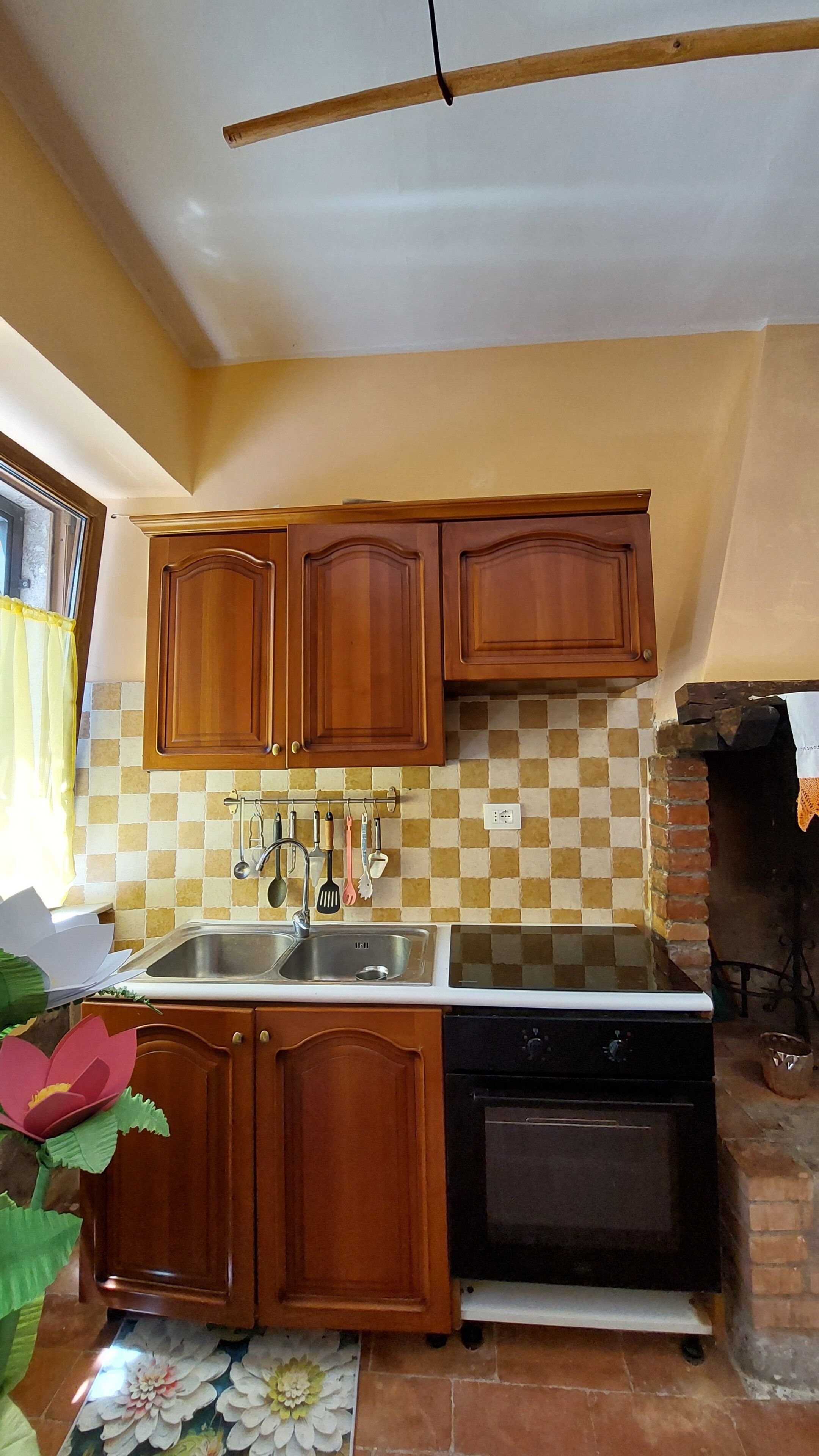 Una cucina con mobili in legno, un lavello, un fornello e una schiena di cucina rivestita di piastrelle.
