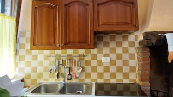 Una cucina con mobili in legno, un lavello, un fornello e una schiena di cucina rivestita di piastrelle.