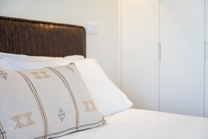 Ein Bett mit einem gemusterten Kopfkissen und einem schlichten weißen Kissen.