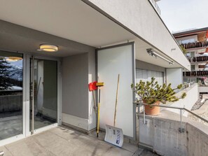 A modern building entrance with a glass door, a potted plant, and cleaning tools. - Casa Bella Appartement/Fewo, Dusche oder Bad, WC, 8-Bettwohnung by Interhome (Arosa)