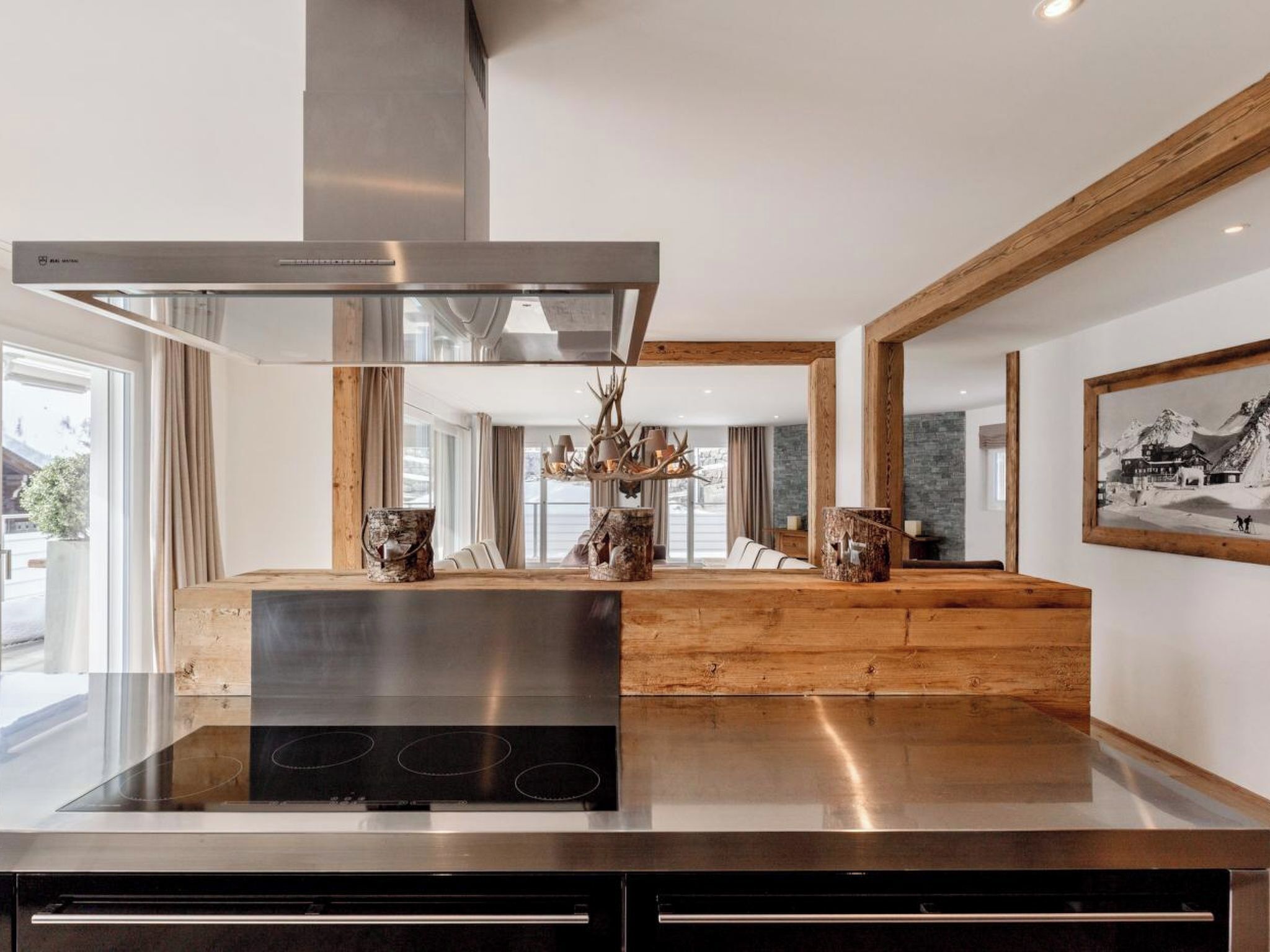 Een moderne keuken met een roestvrijstalen afzuigkap, houten details en een centraal eiland met decoratieve objecten.