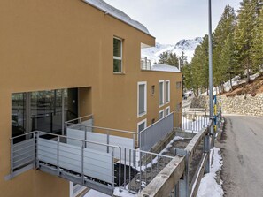 Ein modernes Gebäude mit flachem Dach, großen Fenstern und einer Metalltreppe, die zu einem Balkon führt.