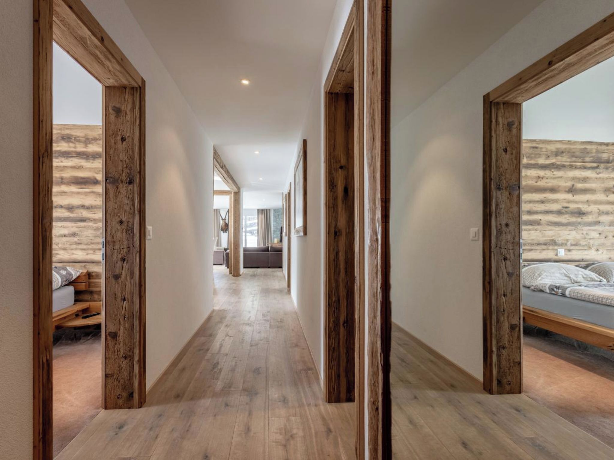 Un pasillo con vigas de madera, una cama con almohadas y un sofá al fondo.