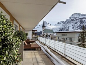 Ein Balkon mit Blick auf schneebedeckte Berge und eine Kirche mit einem Glockenturm.