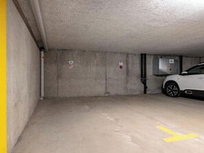 Eine Parkgarage mit Betonwänden, nummerierten Stellplätzen und einem weißen Auto, das auf Platz 19 steht.