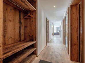 Ein Korridor mit Holzwandverkleidung, einem Kleiderständer und Blick in einen Raum mit Bett und Fenster.