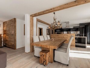 Ein Essbereich mit einem großen Holztisch, gepolsterten Stühlen und einem rustikalen Kronleuchter.