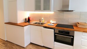 A modern kitchen with white cabinetry, a wooden countertop, a stainless steel sink, a coffee maker, and a built-in oven. - Jäggi 44 by Arosa Holiday Appartement/Fewo, Dusche und Bad, WC, 3-Bettwohnung by Interhome (Arosa)