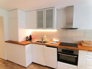 A modern kitchen with white cabinetry, a wooden countertop, a stainless steel sink, a coffee maker, and a built-in oven. - Jäggi 44 by Arosa Holiday Appartement/Fewo, Dusche und Bad, WC, 3-Bettwohnung by Interhome (Arosa)