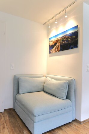 A light-colored sofa in a room with a wooden floor and a wall-mounted picture. - Jäggi 44 by Arosa Holiday Appartement/Fewo, Dusche und Bad, WC, 3-Bettwohnung by Interhome (Arosa)