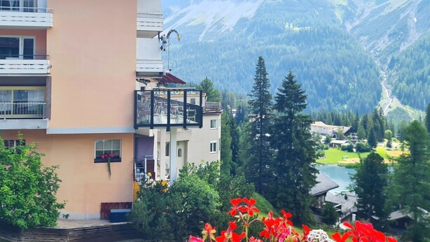 A hotel with a balcony, a mountain view, and a river in the background. - Jäggi 44 by Arosa Holiday Appartement/Fewo, Dusche und Bad, WC, 3-Bettwohnung by Interhome (Arosa)