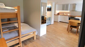 A compact room with a bunk bed, a dining area, and a kitchenette. - Jäggi 44 by Arosa Holiday Appartement/Fewo, Dusche und Bad, WC, 3-Bettwohnung by Interhome (Arosa)