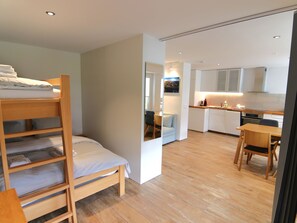 A compact room with a bunk bed, a dining area, and a kitchenette. - Jäggi 44 by Arosa Holiday Appartement/Fewo, Dusche und Bad, WC, 3-Bettwohnung by Interhome (Arosa)