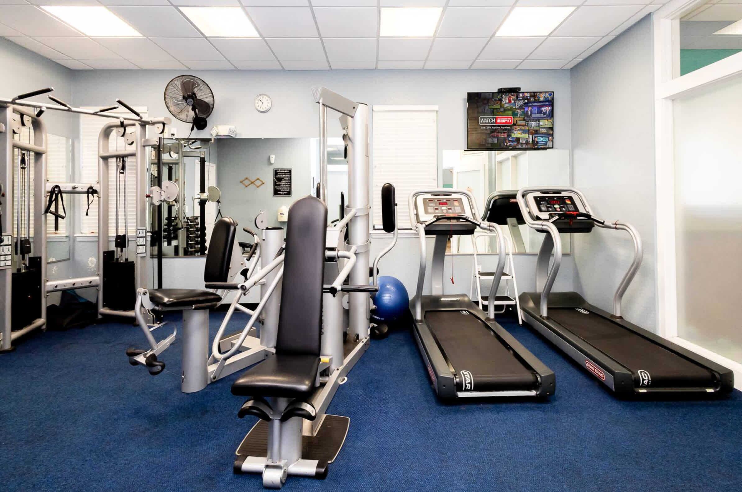 A gym with cardio equipment, weight machines, and a treadmill.