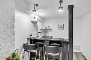 A kitchen with a bar area, two bar stools, a sink, and pendant lighting. - The Sweet Little White One by Crafty Casitas (Oklahoma City)