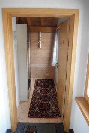 Ein schmaler Korridor mit Holzwänden und einem gemusterten Teppich auf dem Boden.