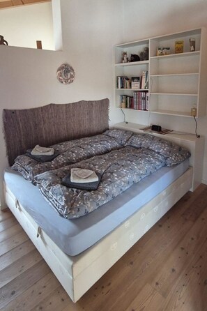 Ein Schlafzimmer mit einem Bett, einem Bücherregal und Holzboden.