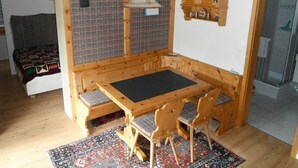 Um quarto aconchegante com área de estar com bancos de madeira, uma mesa pequena e um tapete estampado.