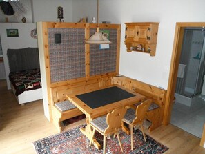 Ein gemütliches Zimmer mit einer Holzbank, einem kleinen Tisch und einem gemusterten Teppich.
