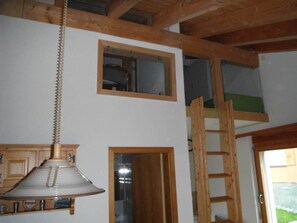 A room with a wooden ceiling, a hanging light fixture, a wooden ladder, and a door leading to another room. - Casa Cresta B72 Appartement/Fewo,  , 2-Bettwohnung 2-Bettwohnung by Interhome (Arosa)
