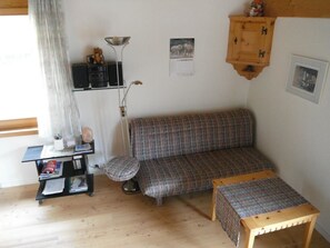 Ein gemütliches Wohnzimmer mit einer Couch, einem kleinen Tisch, einer Lampe und einem Schrank.