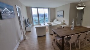 Un appartement moderne comprenant un coin repas, un salon avec un canapé et une vue sur la ville, ainsi qu’une grande fenêtre.