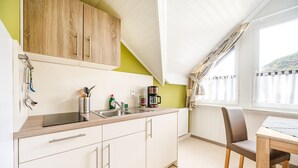 Eine Küche mit weißen Schränken, einer Holzarbeitsplatte, einer Kaffeemaschine und einem Fenster mit Vorhängen.
