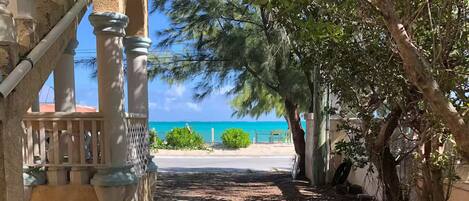 A pathway leading to a building with columns and a view of the ocean.