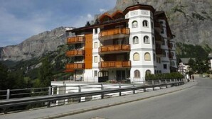 Ein mehrstöckiges Hotel mit Balkonen vor einer gebirgigen Kulisse.