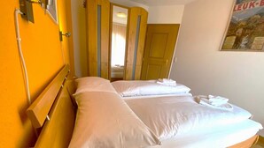 Ein Hotelzimmer mit einem hölzernen Bett, weißen Laken, einem Spiegel und einer Tür mit Spiegel.