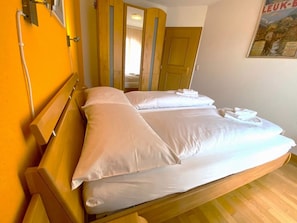 Ein Hotelzimmer mit einem hölzernen Bett, weißen Laken, einem Spiegel und einer Tür mit Spiegel.