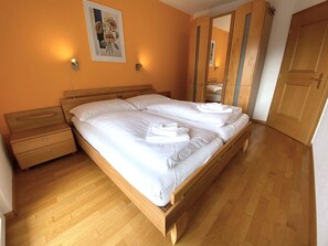 Ein Schlafzimmer mit einem hölzernen Bett, einem Nachttisch, einer Kommode und einer Tür.
