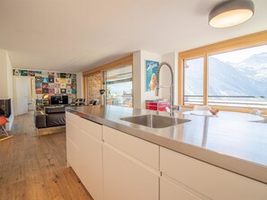 A modern kitchen with a large island, a dining area with a view, and a living space with a wall of posters. - Salis 06 by Arosa Holiday Appartement/Fewo, Dusche und Bad, WC, 3 Schlafräume by Interhome (Arosa)