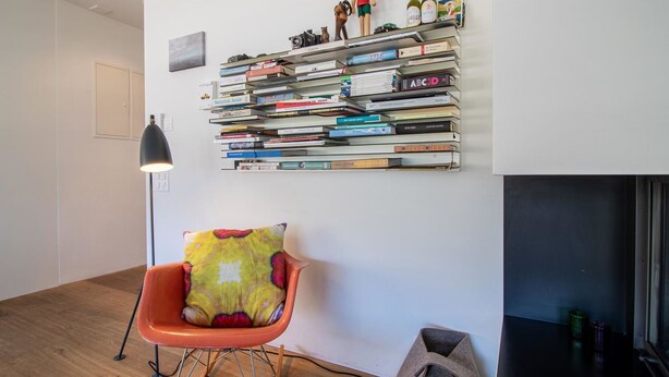 A modern living room with a bookshelf, a chair, and a fireplace. - Salis 06 by Arosa Holiday Appartement/Fewo, Dusche und Bad, WC, 3 Schlafräume by Interhome (Arosa)