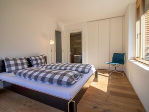 Ein Schlafzimmer mit einem Bett, einem Sessel und einem Fenster.