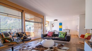 A modern living room with a leather sofa, a round ottoman, and a cowhide rug. - Salis 06 by Arosa Holiday Appartement/Fewo, Dusche und Bad, WC, 3 Schlafräume by Interhome (Arosa)